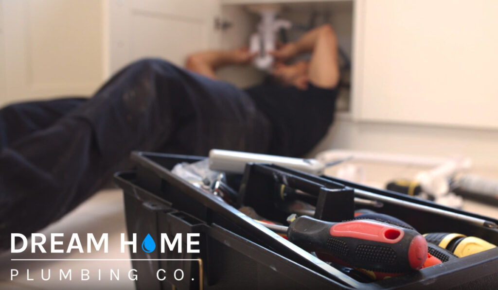A man repairing the pipes under the sink. Plumbing services in Glen Ellyn for your home. Call us for affordable plumbing services.