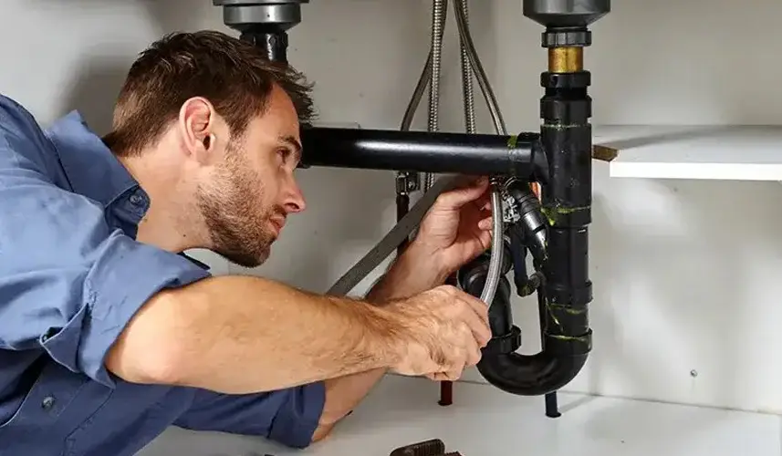 Local plumber repairing under kitchen sink. Exemplary emergency plumbing services, ensuring quality and satisfaction.